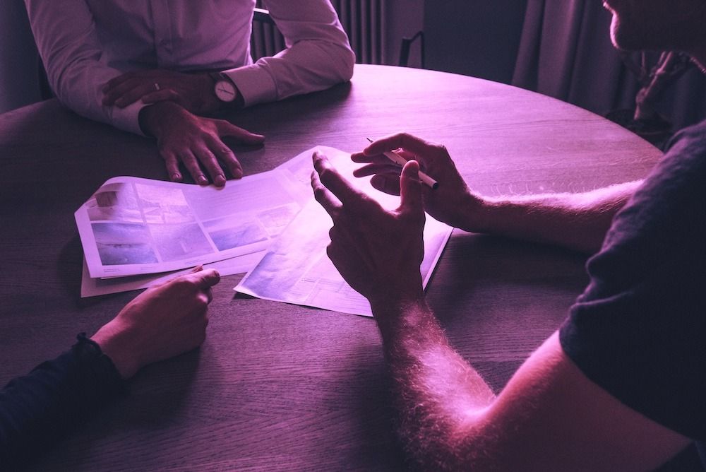 Business handshake over documents at conference table with purple lighting - accounting partnerships and consultation services for creative businesses