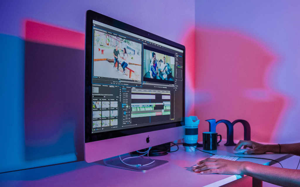 A creative professional editing video on a computer, with colorful lighting in the background, representing the digital and visual industries that rely on specialized accounting services.