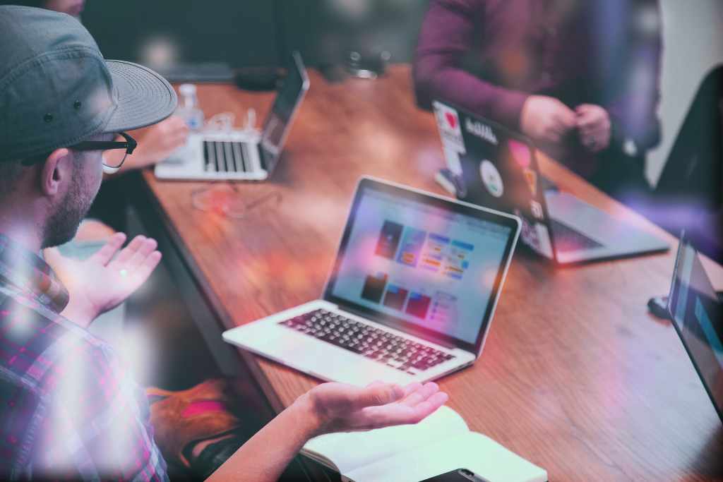 Creative professionals collaborating with laptops and tablets in modern workspace - accounting services for digital agencies and creative teams