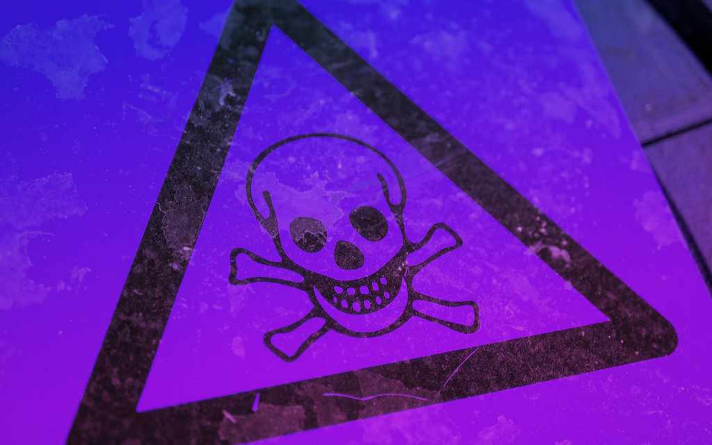 Black triangular warning sign with skull and crossbones symbol on purple background - accounting services for risk management and business compliance for creative professionals