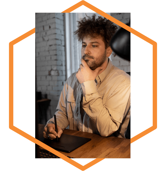 Thoughtful man using digital drawing tablet with stylus in modern workspace with brick walls - accounting services for digital artists and illustration professionals