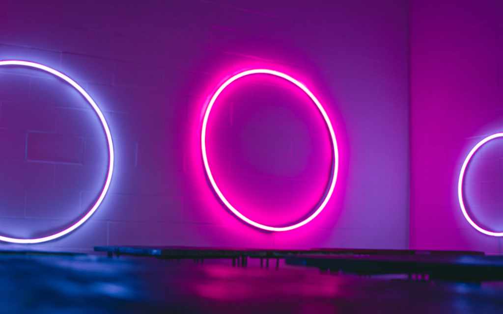 Three circular neon rings in pink and blue with reflective surface below - accounting services for lighting designers and experiential creative professionals