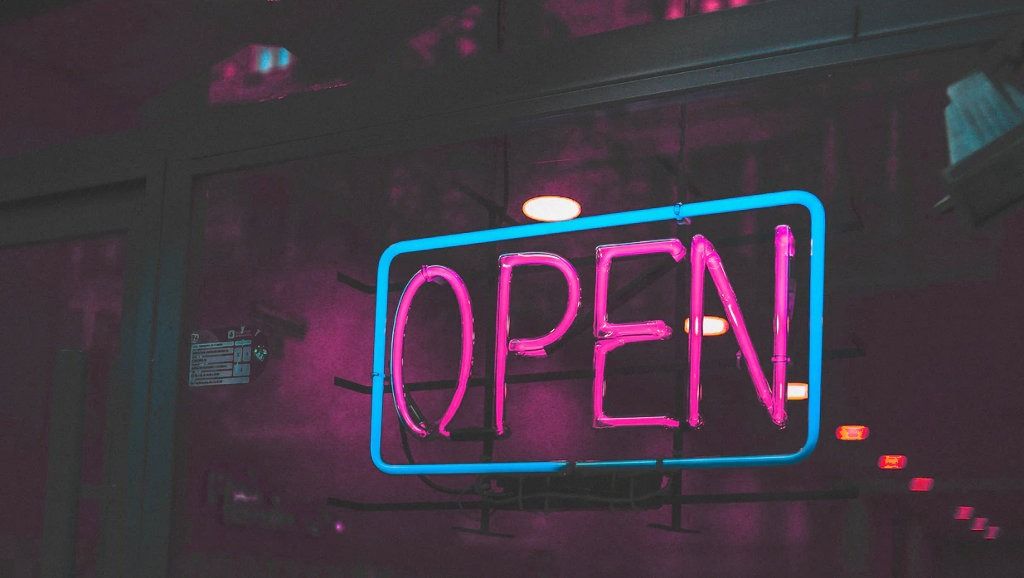 Neon OPEN sign in pink letters - accounting services for creative professionals