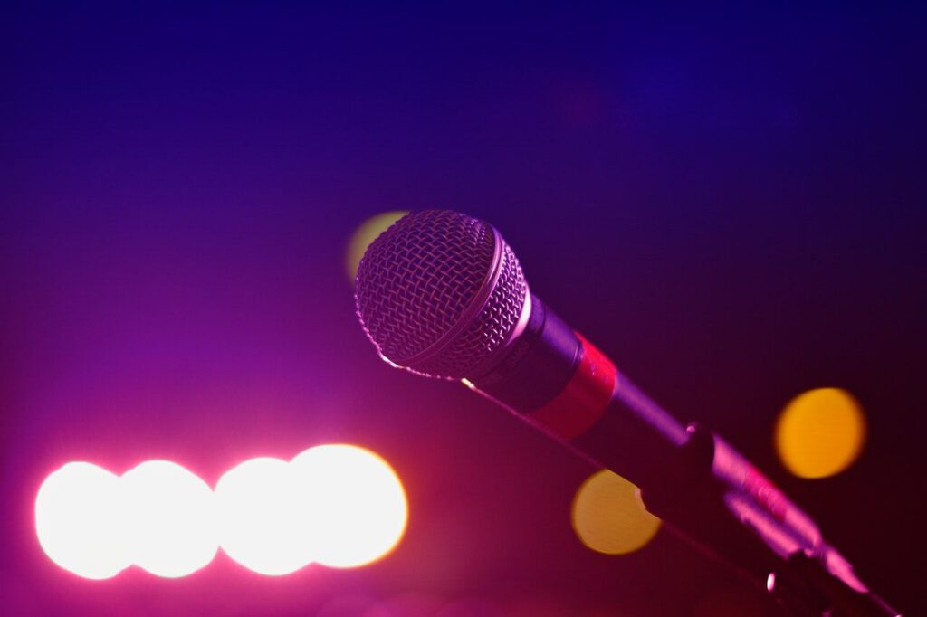 Professional microphone with colorful stage lighting backdrop - accounting services for musicians and entertainment professionals