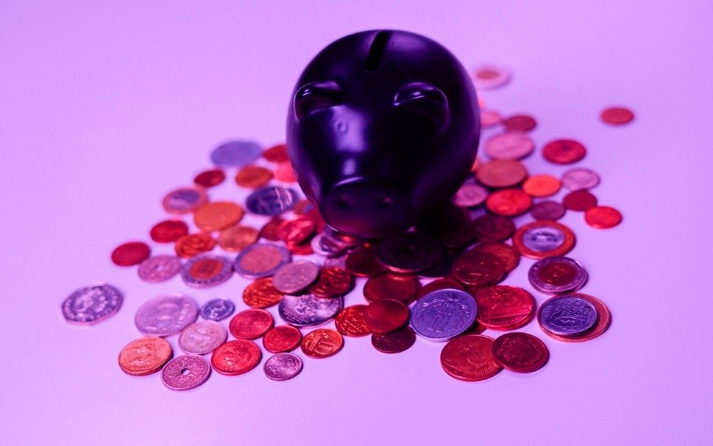 Glossy purple decorative skull with scattered colorful coins on pink background - accounting services for gaming businesses and collectible industry professionals