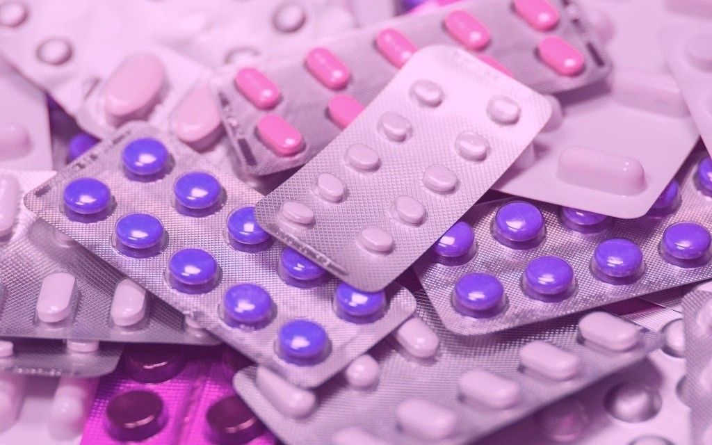 Scattered pharmaceutical blister packs with pink and purple pills in soft lighting - accounting services for healthcare designers and pharmaceutical creative professionals
